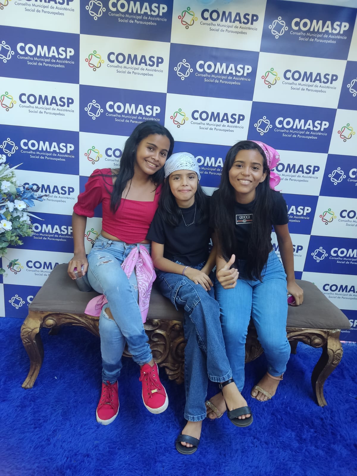 Três jovens participantes da conferência em frente ao painel do COMASP em Parauapebas